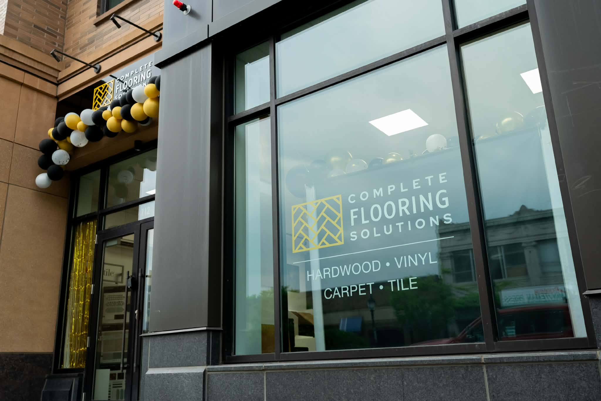 Complete Flooring Solutions showroom window displaying hardwood, vinyl, carpet, and tile services